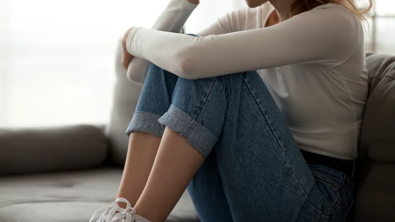 Upset Young Woman Sitting On A Couch